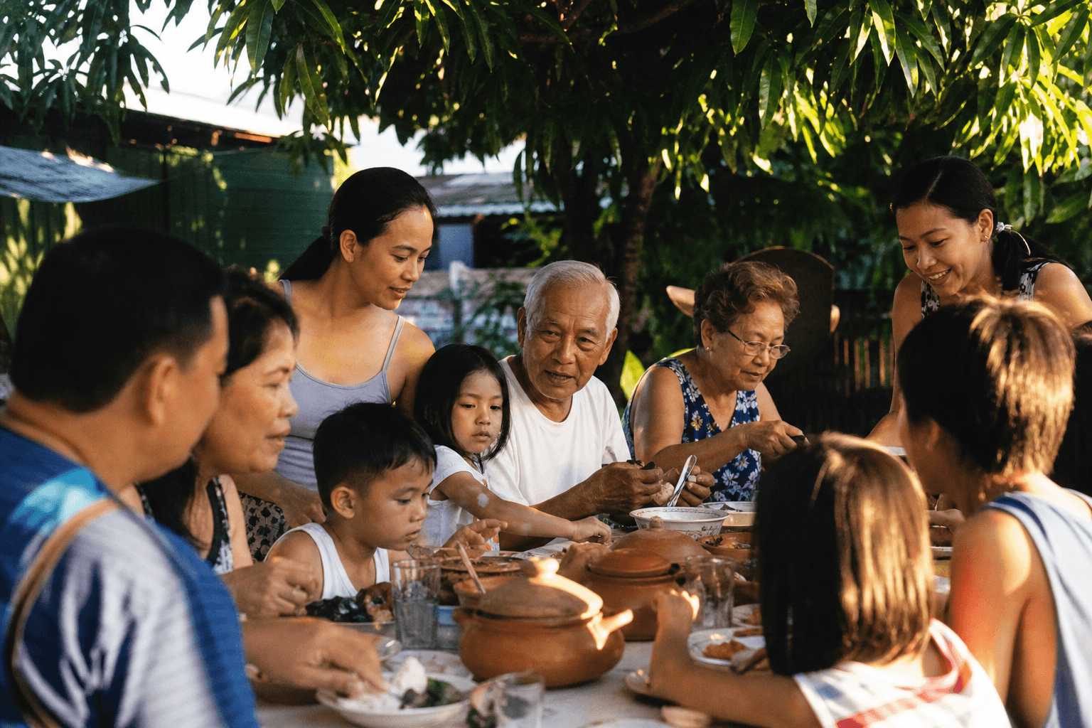 Family gathered around the table beneath a mango tree